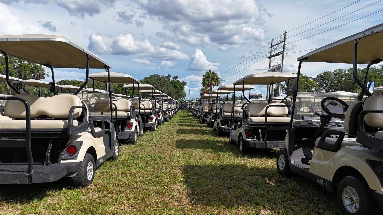 Row of white Club Car golf carts lined up for sale